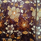 Brown floral blanket with yellow, beige, and white flower patterns on a soft fabric.