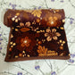 Brown floral blanket rolled on a floral bedsheet, cozy bedding decor