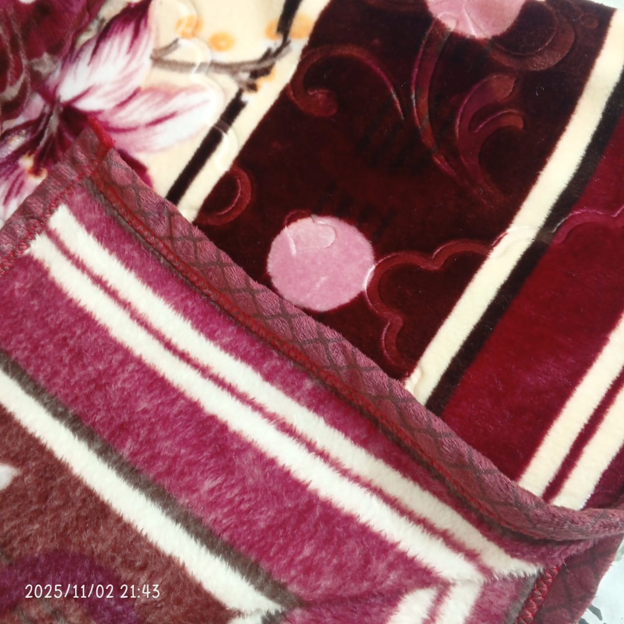 Plush maroon and cream floral blanket with striped and swirl patterns, soft texture