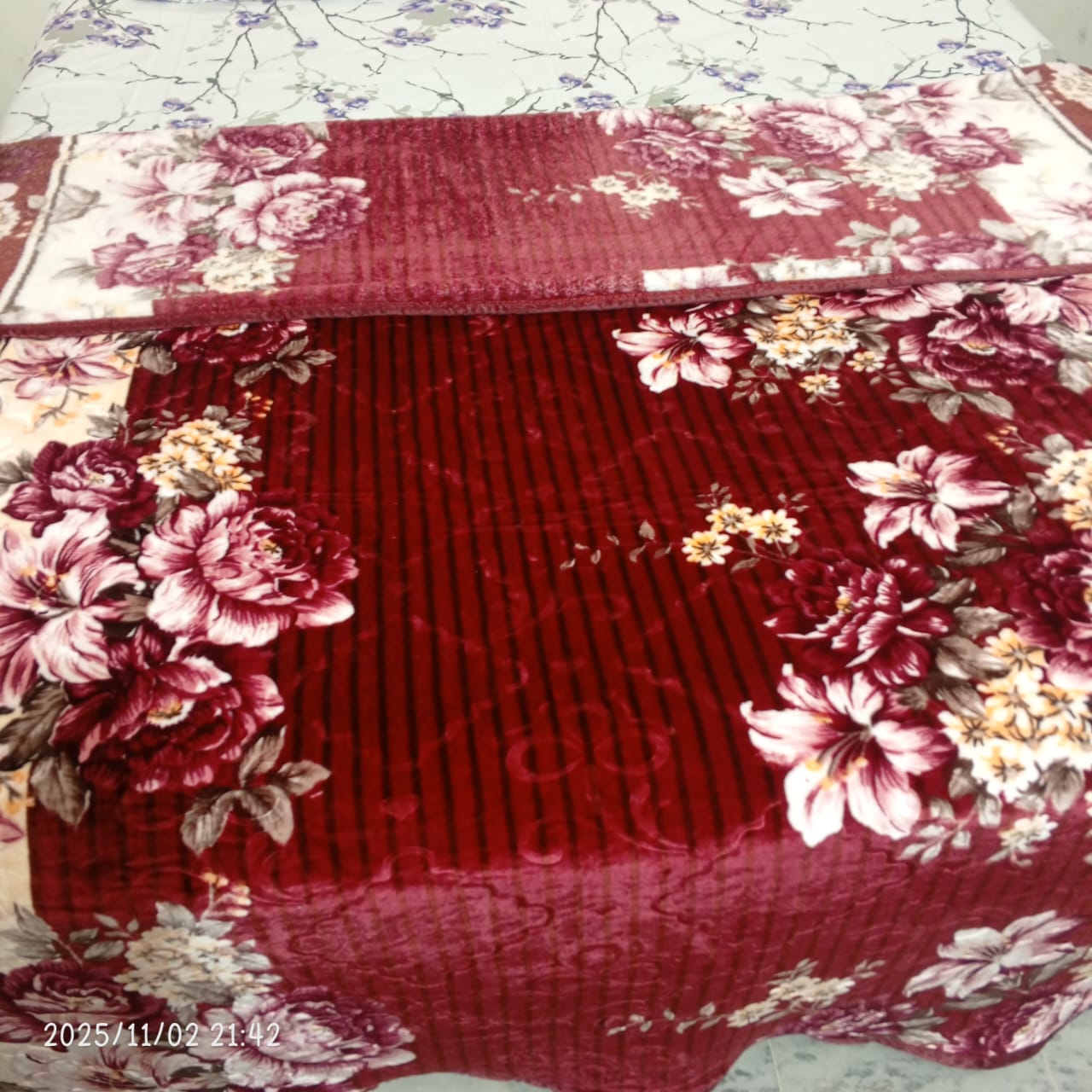Red floral velvet blanket with pink and yellow flowers on a bed, bedroom decor