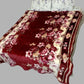 Floral maroon and cream velvet blanket on a double bed with printed pillows