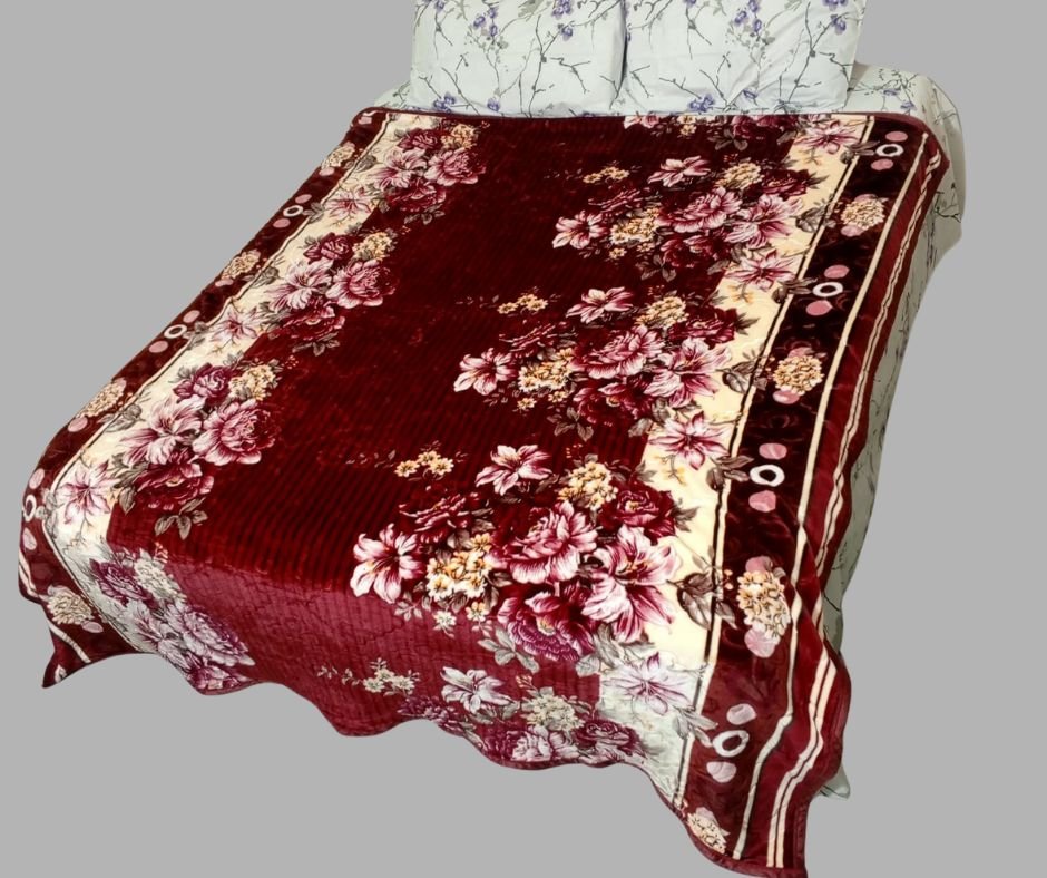 Floral maroon and cream velvet blanket on a double bed with printed pillows