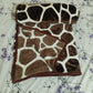 Folded giraffe print fleece blanket on a floral patterned bed sheet