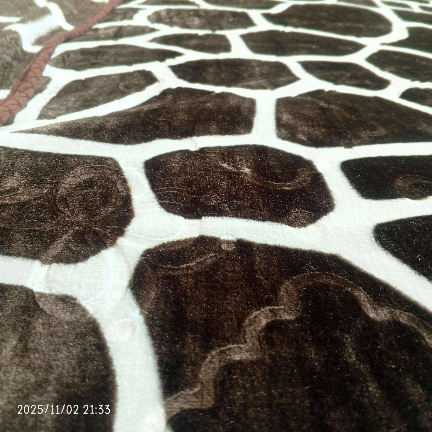 Close-up of a giraffe print fleece blanket with soft brown and white patterns
