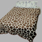 Brown giraffe print bedspread on a bed with floral pillows, gray background