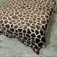 Brown giraffe print blanket on bed over marble floor