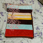 Folded floral striped blanket on a bed with purple blossom bedsheet
