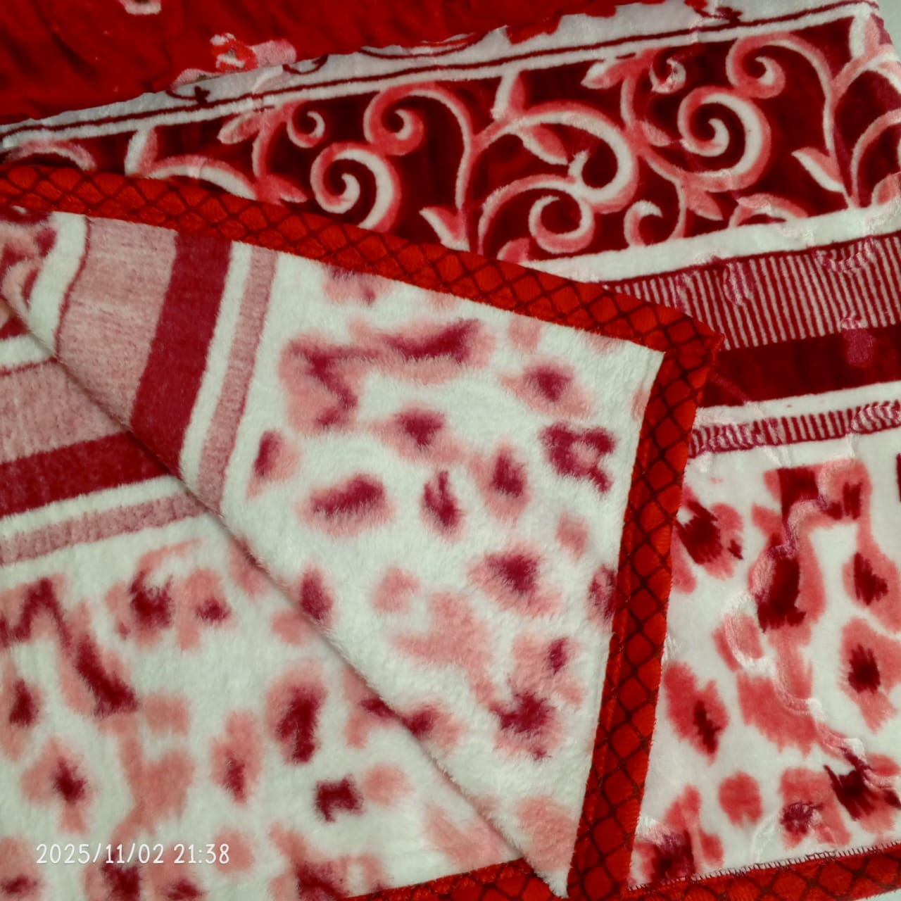 Red and white fleece blanket with floral and geometric patterns, soft plush texture
